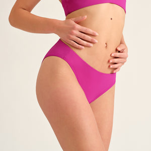Seitliches Hip-shot von einer Frau, die einen Pinken Perioden Badeanzug Slip von Ooia trägt